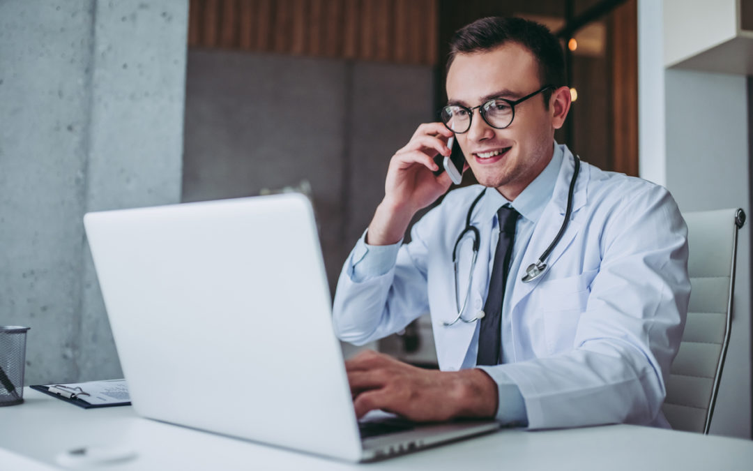 Doctor working with lapton. Talking on mobile phone and smiling.